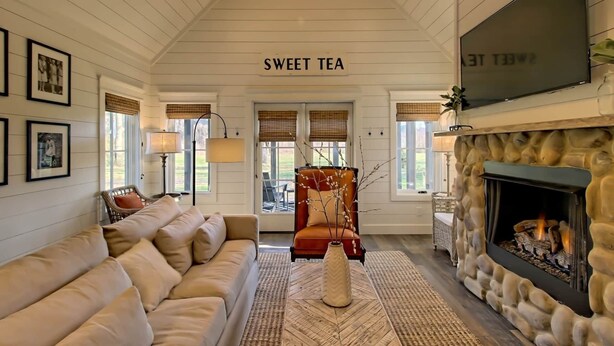 A cozy living room with a fireplace, a sofa, a chair, and a sign that reads "SWEET TEA". - Sweet Tea Cottage at Julep Farms (Dillard)