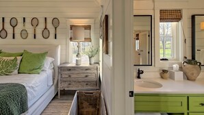 A bedroom with a bed, bedside table, and a dresser. There is a window with a view of the outdoors. - Sweet Tea Cottage at Julep Farms (Dillard)