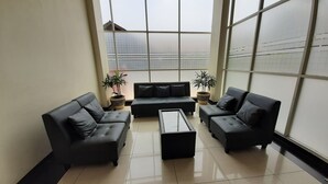 Una sala de estar moderna con un ventanal grande, dos sofás, una mesita de centro y dos plantas en macetas.