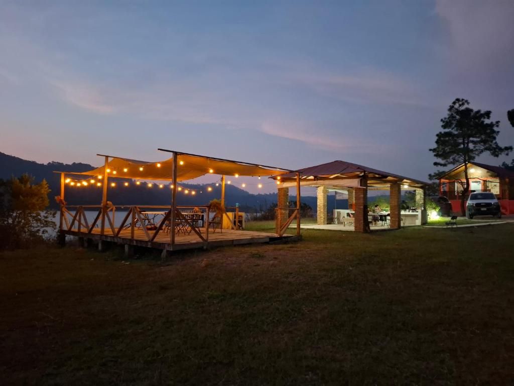 Un espacio al aire libre techado, con luces colgantes, una terraza de madera y un edificio con tejado rojo.