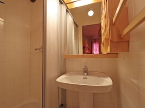 Une salle de bain avec un lavabo blanc, un miroir et une douche.