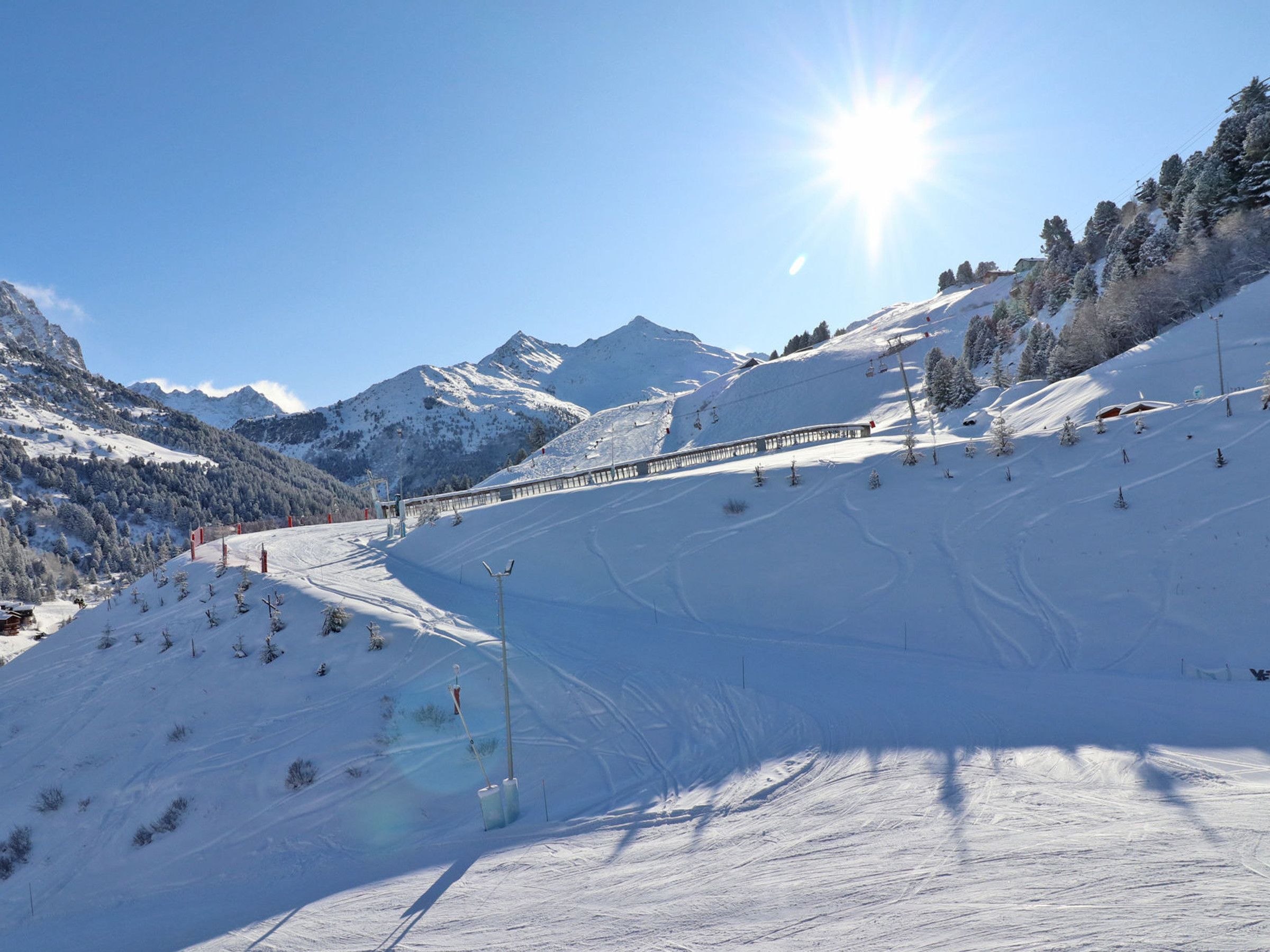 A snow-covered ski slope with a ski lift and a mountain backdrop.
