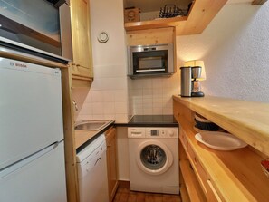 A compact kitchen with a Bosch refrigerator, a washing machine, a microwave, and a coffee maker. - Family duplex on the slopes, ideal for 7 people (Méribel)