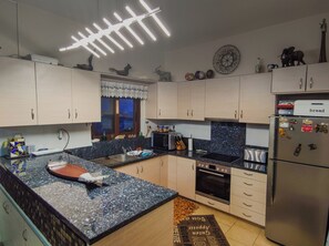 Eine moderne Küche mit Granit Arbeitsplatten, Edelstahlgeräten und Dekoration an der Wand.