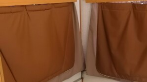 Un lit simple avec une tête de lit en bois et des rideaux marron.