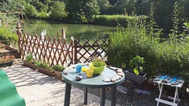 Une table ronde recouverte d’une nappe verte, avec un saladier et divers objets posés dessus.