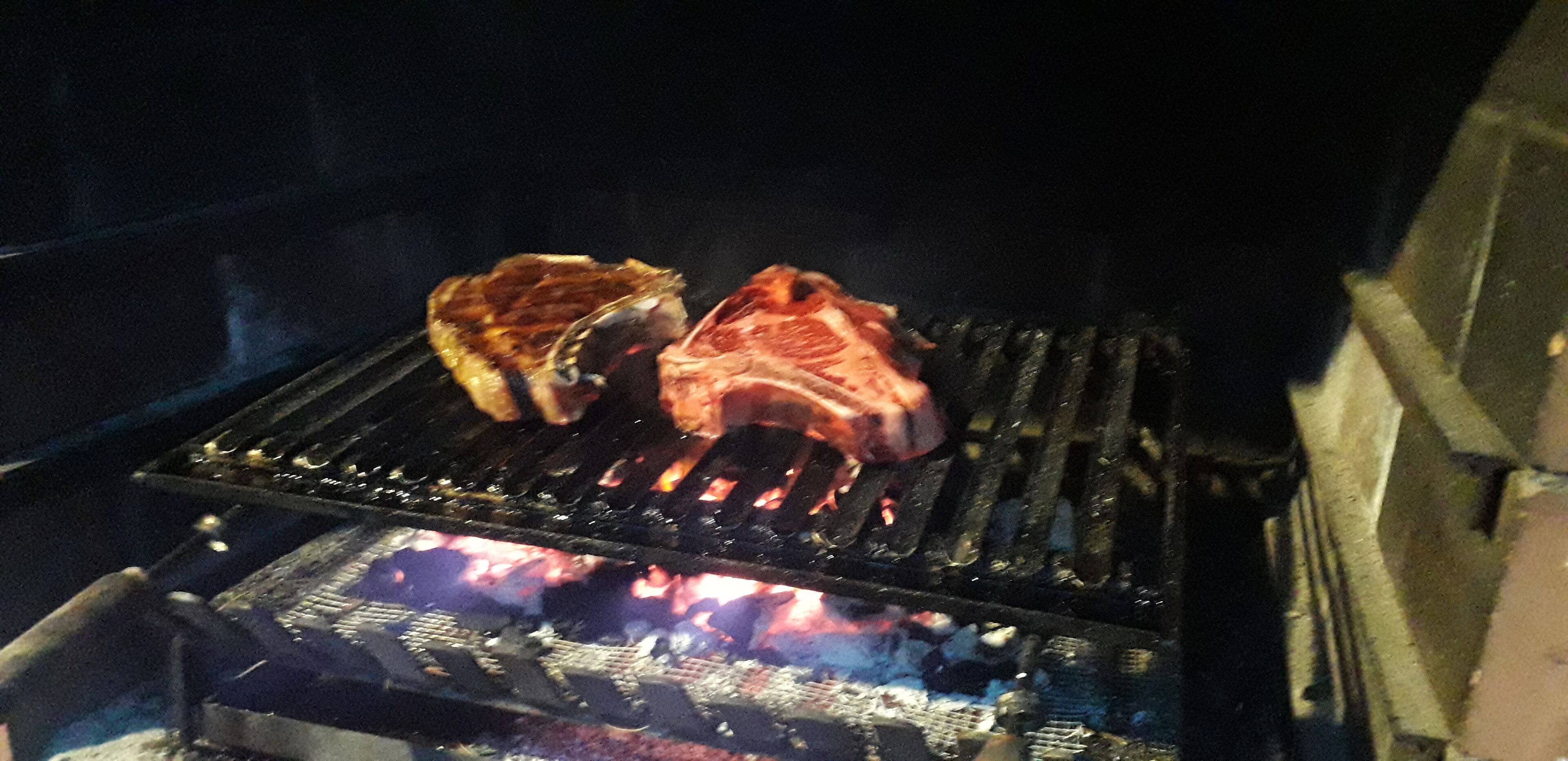 Ein Grill mit zwei Fleischstücken, die über offenem Feuer gegart werden.