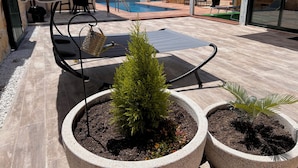 A patio area with a pool, outdoor furniture, and potted plants.
