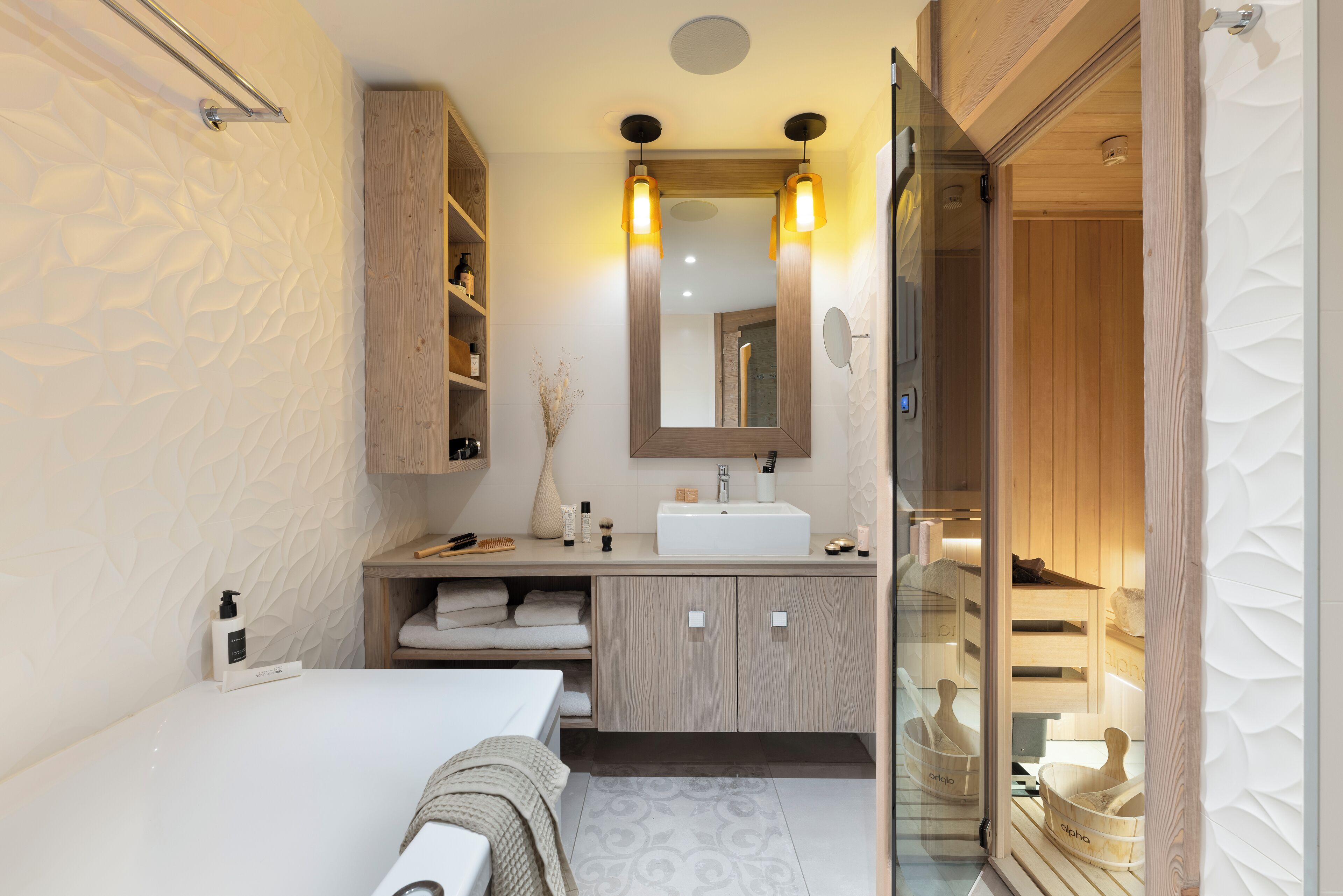 A modern bathroom with a white bathtub, wooden vanity, and a large mirror.