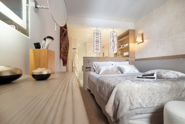 Un dormitorio moderno con una cama grande, mesitas de noche, un espejo y un armario.