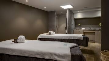 Relax in a serene spa room with two massage tables, a sink, and a peaceful atmosphere.