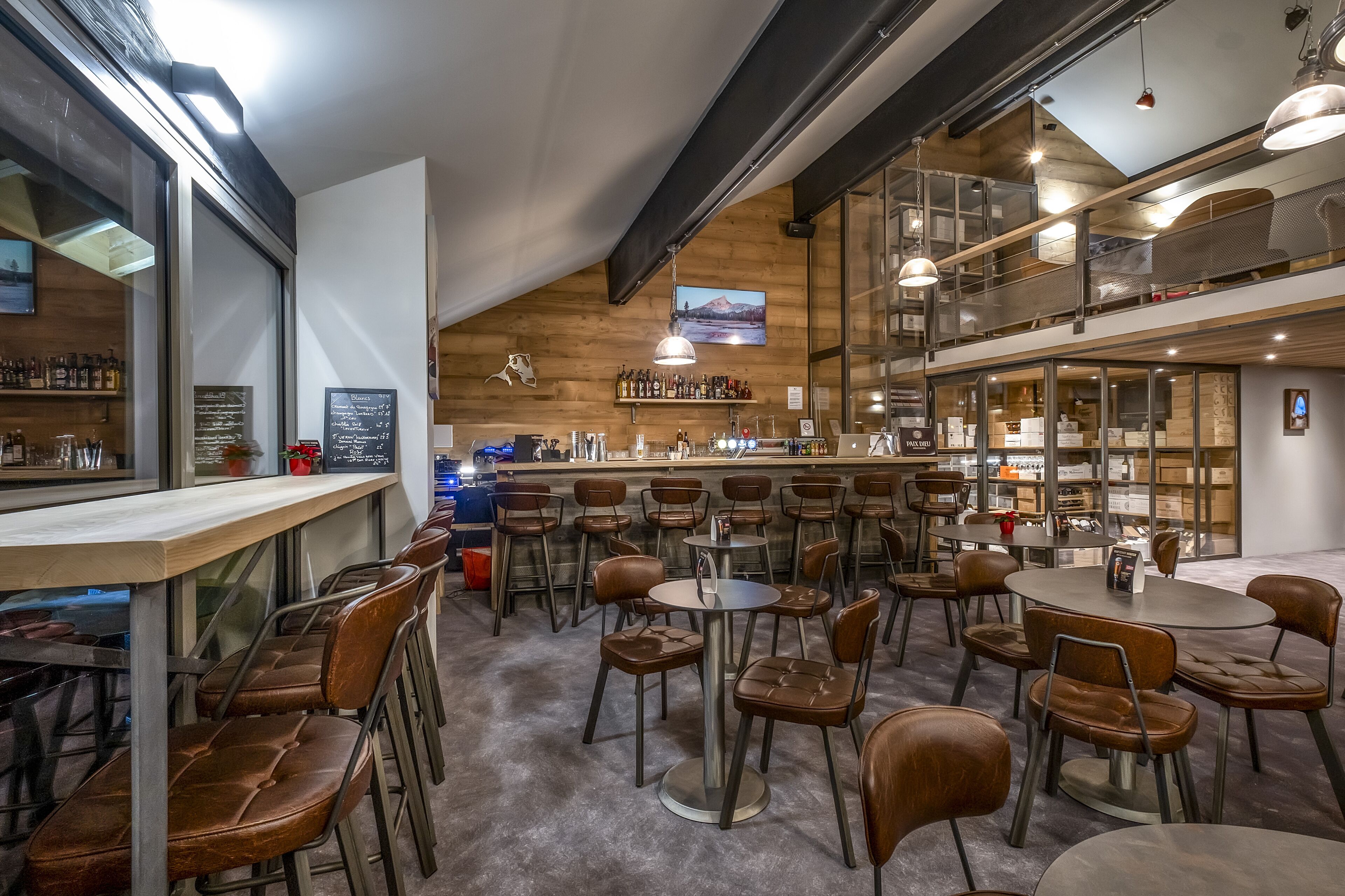 A spacious café with multiple seating areas, a bar, and a visible kitchen area.