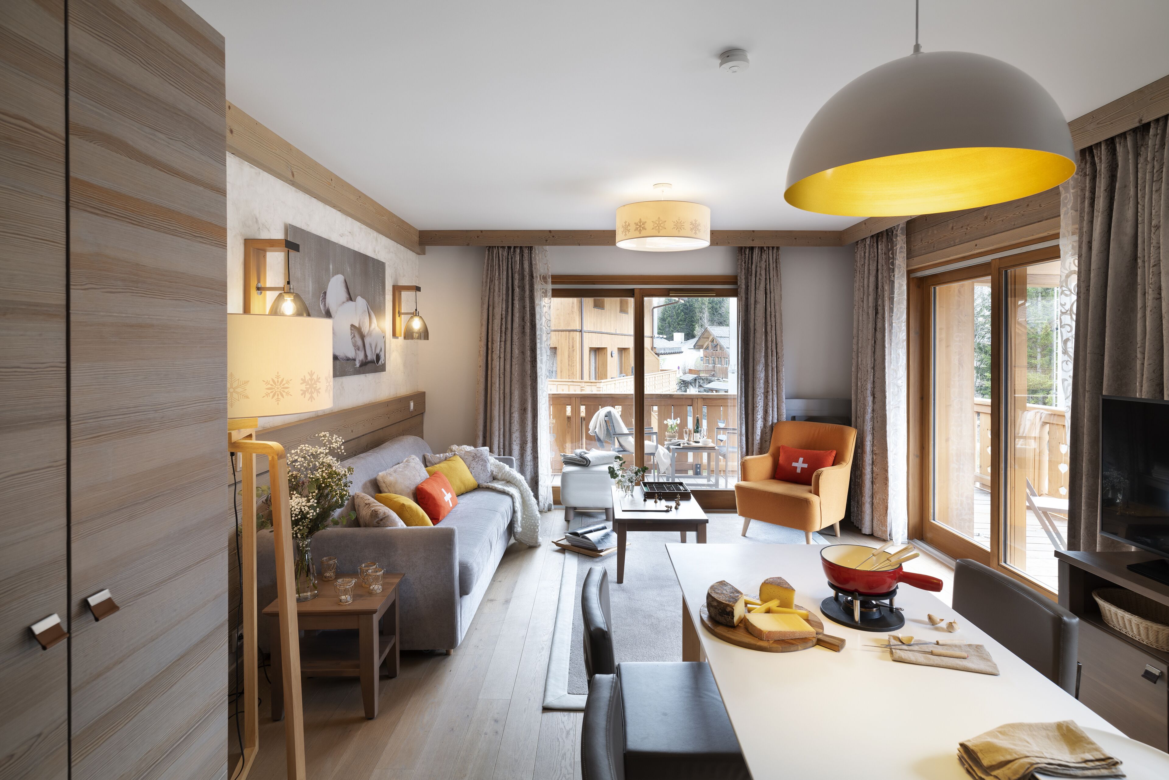 A modern living room with a sofa, armchairs, a dining table with a red pot, and a large window with curtains.