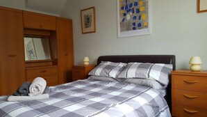 Una camera da letto con un letto, un'armadio in legno, comodini e opere d'arte alle pareti.
