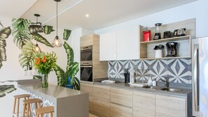A modern kitchen with a central island, wooden cabinets, and a geometric backsplash. - Beautifully Minimalistic Studio Wrapped in Nature by Stella Rentals (Tulum)