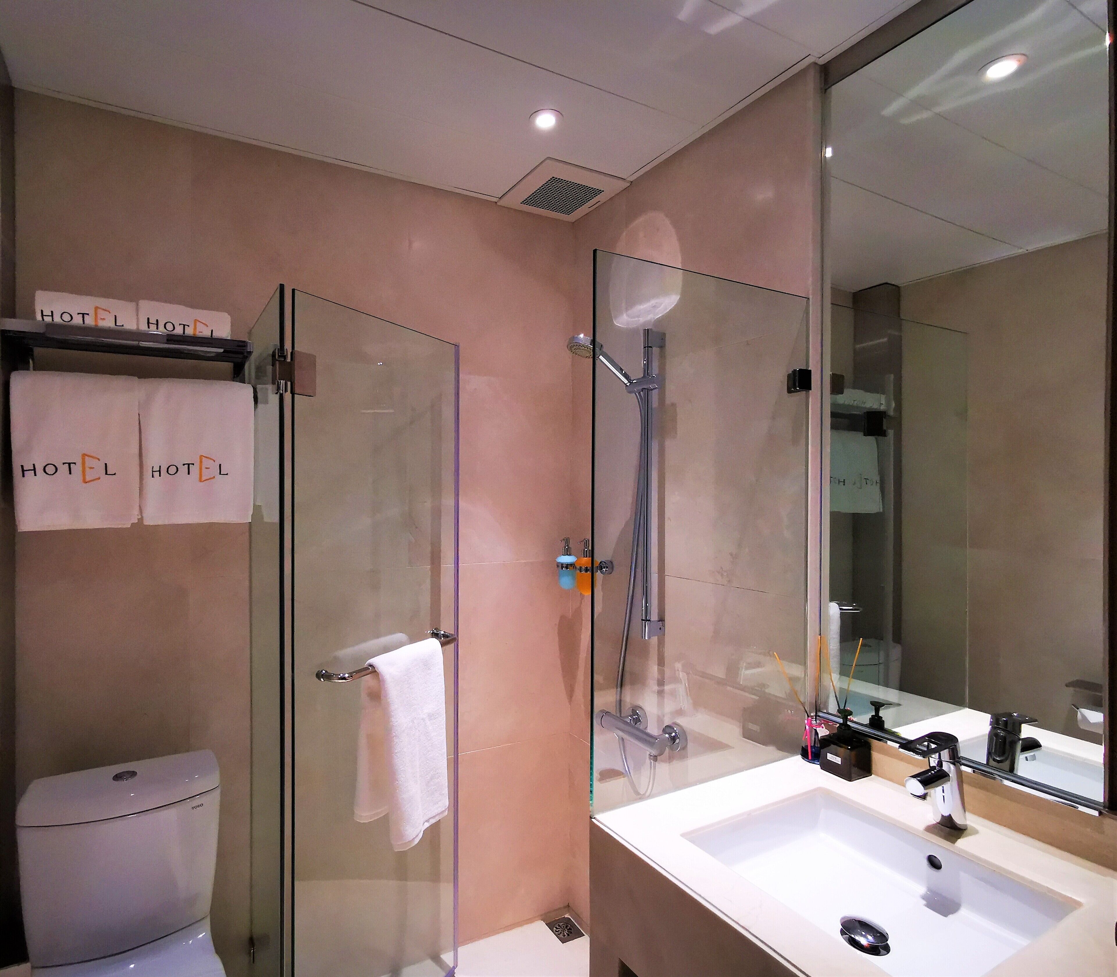 A modern bathroom with a glass shower enclosure, a white sink, and a toilet.