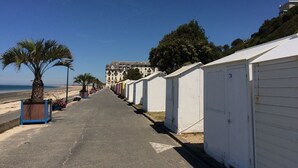 A seaside road lined with white mobile homes, a palm tree, and a building in the background. - ~ Beachfront 2 ~ view and direct access to the sea * ~ ¤ (Donville-les-Bains)