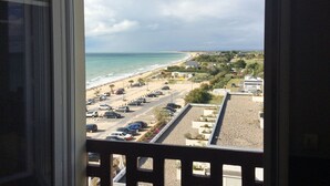 A view from a window overlooking a beach with parked cars and buildings in the distance. - ~ Beachfront 2 ~ view and direct access to the sea * ~ ¤ (Donville-les-Bains)