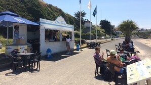 A roadside café with outdoor seating, a menu board, and flags. - ~ Beachfront 2 ~ view and direct access to the sea * ~ ¤ (Donville-les-Bains)