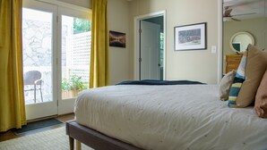 A bedroom with a bed, a door to a balcony, and a wall-mounted picture.