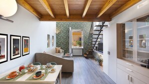 Una cucina moderna con zona pranzo, travi in legno al soffitto e vista su un giardino da un'apertura.