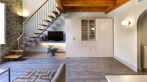 Un interno moderno con una scala in legno, una televisione a schermo piatto, mobili bianchi e un tappeto a motivi.