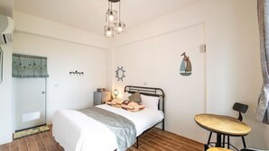 A bedroom with a bed, bedside table, lamp, and a small round table with a chair. - Traditional Arts Country Inn (Wujie)
