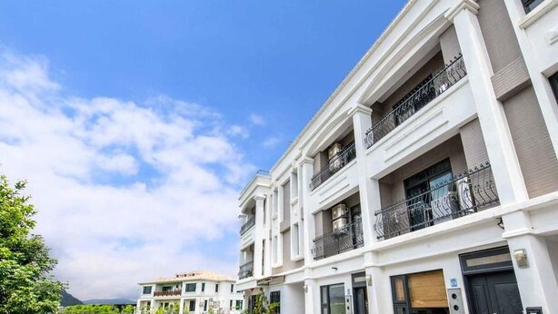 A multi-story residential building with balconies, a flat roof, and a clear sky. - Traditional Arts Country Inn (Wujie)