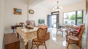 A spacious living area with a dining table, wicker chairs, a sofa, and a television. - Traditional Arts Country Inn (Wujie)