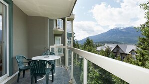 Un balcone con tavolo e sedie, affacciato su un paesaggio montuoso.