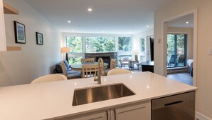Een moderne keuken met een centraal eiland, een eethoek met een ronde tafel en een open haard.