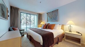 Ein Hotelzimmer mit einem großen Bett, einem Schreibtisch, einem Stuhl, einem Nachttisch mit Lampe und einem Gemälde an der Wand.
