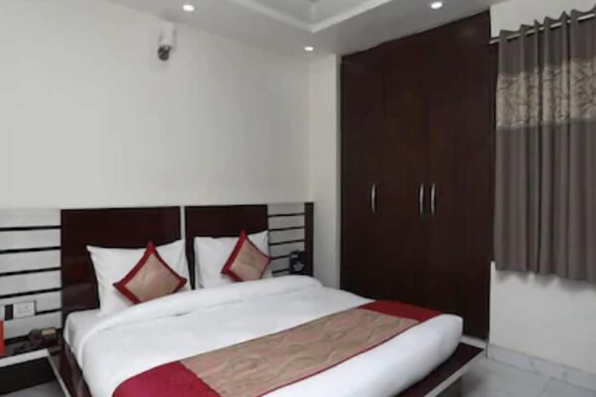 A hotel room with a large bed, wooden headboard, and a wardrobe.