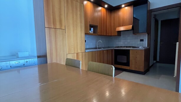 Eine moderne Küche mit Holzausstattung, einem Esstisch und einem eingebauten Backofen.