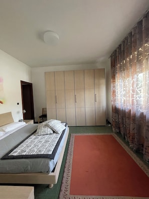 Ein Schlafzimmer mit Bett, Kleiderschrank, Schreibtisch und Stuhl.