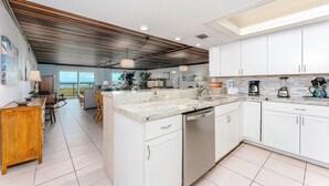 A modern kitchen with white cabinets, a marble countertop, and stainless steel appliances. - Seagull 202 - Quiet Beachfront Hideaway with Endless Ocean Views, Swimming Pool, Spa, Washer/Dryer (South Padre Island)