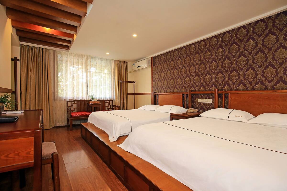 A hotel room with two beds, a desk, and a chair.