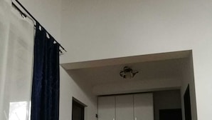 Une pièce avec un plancher en bois, une table sombre, un rideau blanc et une armoire à portes coulissantes.