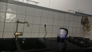 Une cuisine avec un évier noir, une cuisinière à gaz et une machine à café.