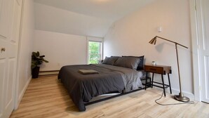 Une chambre à coucher avec un lit, une table de chevet, une lampe et une plante en pot.