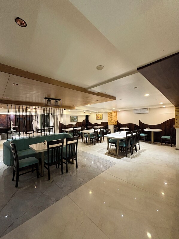 A spacious restaurant with high ceilings, modern lighting, and a mix of booth and table seating.