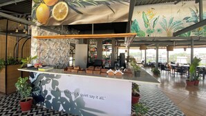 Un área de bar moderna con mostrador, asientos y un mural de plantas tropicales.