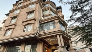 Un edificio de varios pisos con entrada en esquina, ventanas amplias y varios balcones.