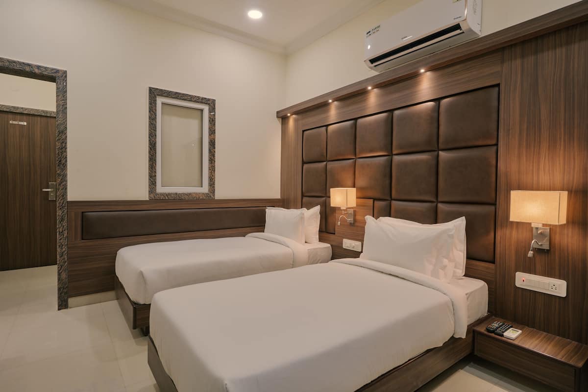 A hotel room with two beds, a mirror, a wall-mounted air conditioner, and bedside lamps.
