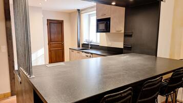 A modern kitchen with a large island, built-in appliances, and a window.