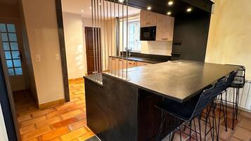 Una cocina moderna con una isla central, taburetes de bar y vista al área de comedor.