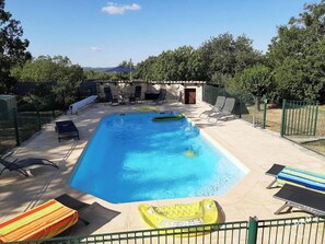 Une piscine rectangulaire à l’eau d’un bleu cristallin, entourée de chaises longues et de transats.