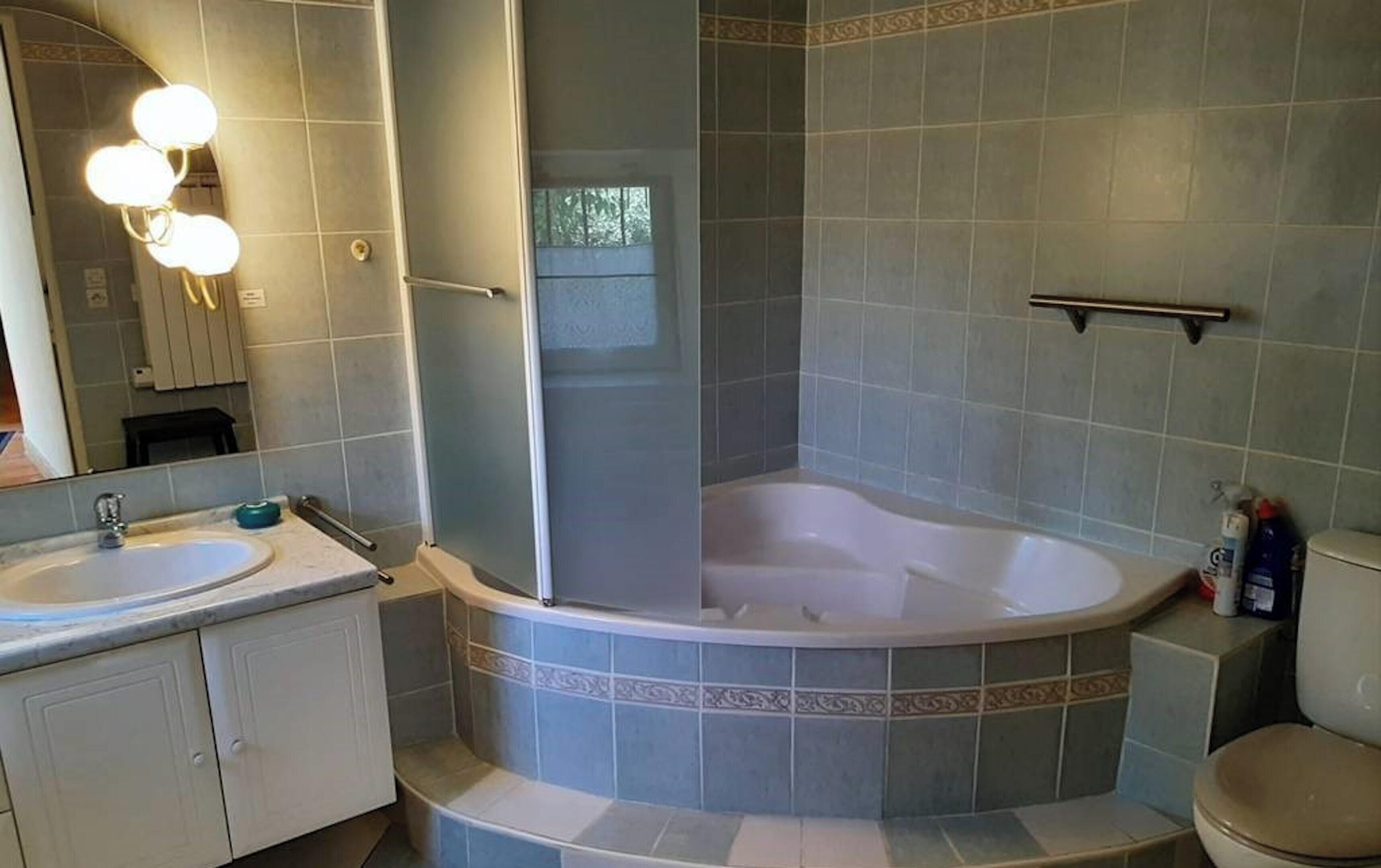 Une salle de bain avec une douche d’angle, une baignoire et des toilettes.