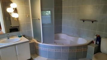 Une salle de bain avec une douche d’angle, une baignoire et des toilettes.