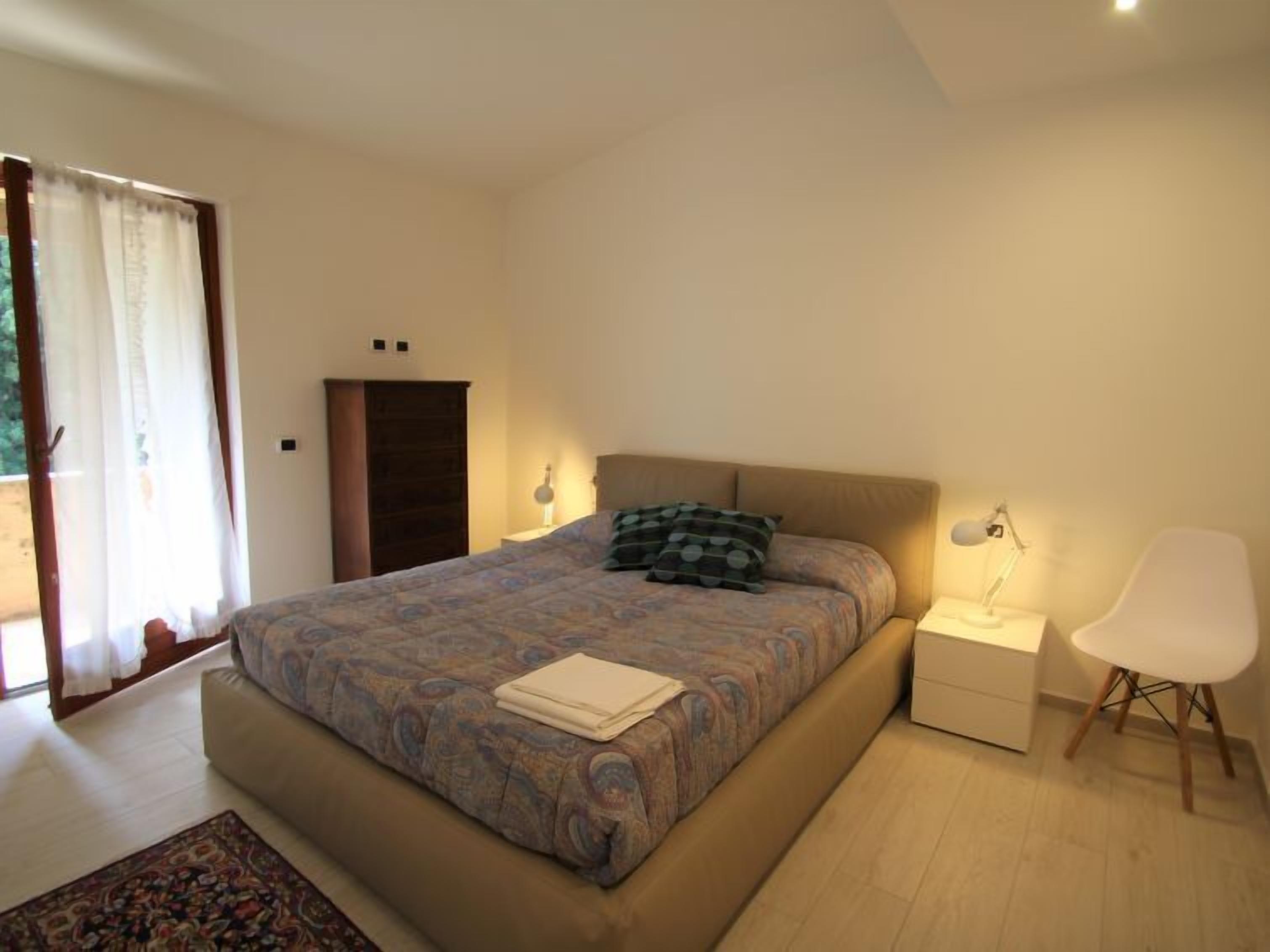 Una camera da letto con un letto, comodini, una sedia e un armadio.